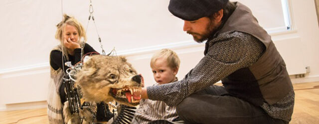 The artists and their young son sitting around a mechanical sculpture of a wolf